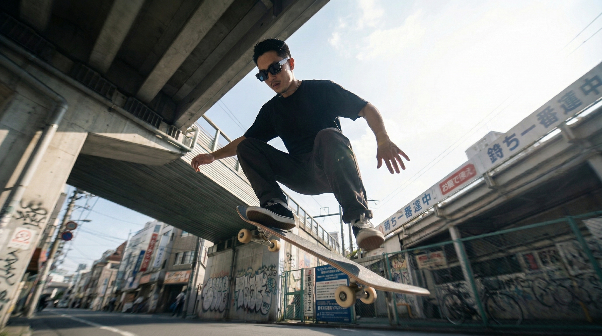 Skateboarder performing a trick under an overpass in an urban setting